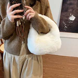White fluffy faux fur handbag with soft crescent shape carried by a model in warm setting