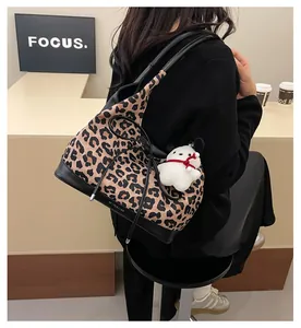 Detail of leopard print tote bag with plush dog charm for daily commute and fashion