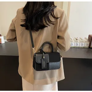 Detalle de bolso bandolera negro con texturas de cuero y herrajes dorados en la correa