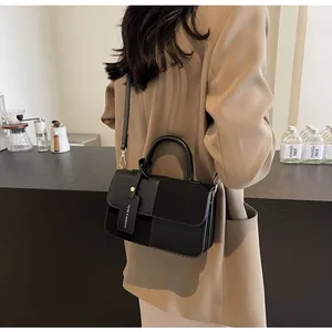 Detalle del bolso bandolera negro con mezcla de texturas de cuero y etiqueta de moda