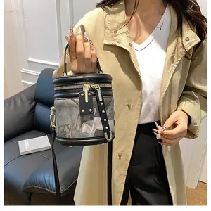 Chic cylindrical bucket bag with grey denim and black leather detail held by model