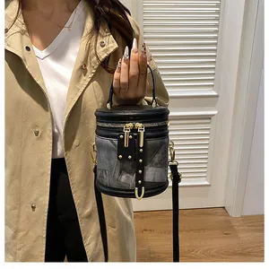 Chic cylinder bucket bag with gold hardware and rivets shown in lifestyle setting