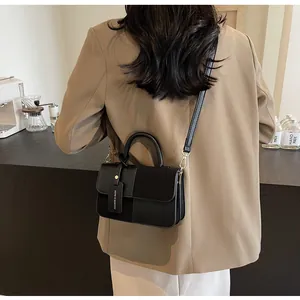 Detalle de mini bolso de piel en contraste con herrajes dorados y etiqueta de moda