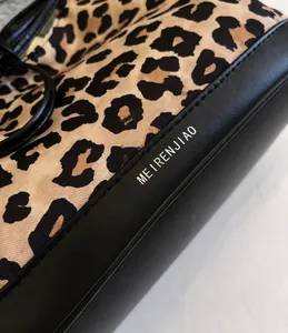 Detail of leopard print tote bag featuring smooth black leather base with white text logo