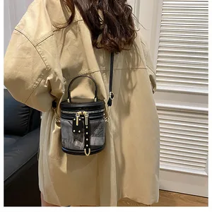 Chic black bucket bag with vintage grey texture and gold hardware held by a model