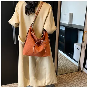 Caramel retro hobo bag with white contrast bow drawstring detail shown on model