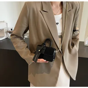 Detalle de mini bolso cuadrado de cuero negro con cadena dorada y etiqueta