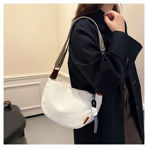 Détail du sac croissant blanc avec bandoulière à motifs et étiquette orange