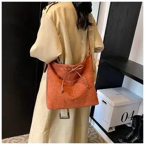 Close-up of caramel faux suede tote bag with white stitching and bow detail
