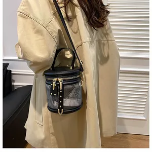 Fashionable grey bucket bag with gold hardware worn by a model in a beige trench coat