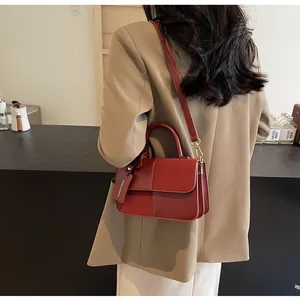 Detalle del bolso de cuero burdeos con etiqueta de moda mostrado en ambiente elegante