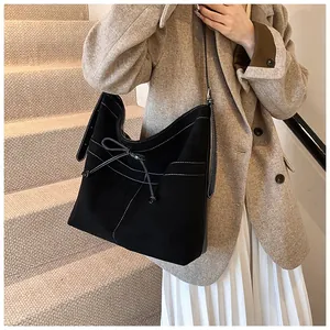 Detail of black matte tote bag with white contrast stitching and bow decoration