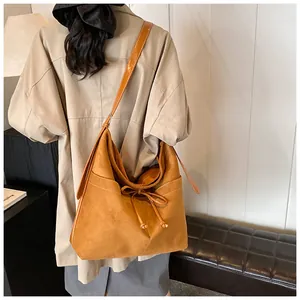 Detail view of large camel suede tote bag with drawstring bow on shoulder model