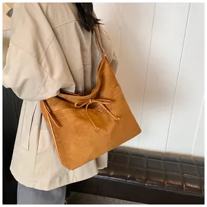 Macro detail of brown suede tote bag featuring white contrast stitching and decorative bow