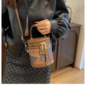 Detailed view of color-block bucket bag with gold rivets and leather top handle