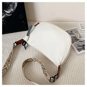 Détail du sac demi-lune blanc avec bandoulière ethnique large et étiquette orange