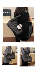Detail of grey leopard print tote bag with plush bear charm and black leather trim accents