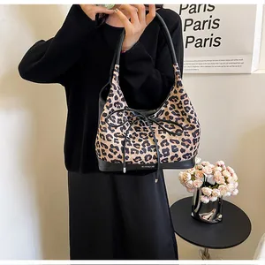 Detail of leopard print tote bag with black ribbon bow and sleek leather trim