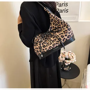 Detail of leopard print tote bag with bow accent and leather base shown in casual setting