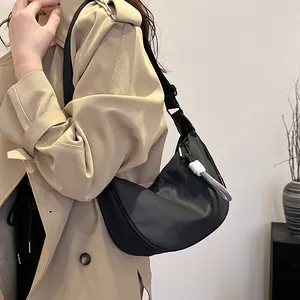Sac hobo demi-lune noir minimaliste avec bandoulière réglable et breloque en corde