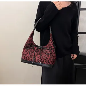 Detail of red leopard print tote bag with black leather base and knot bow accent