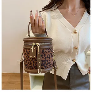 Detail of leopard print bucket bag with gold studs and smooth brown leather trim