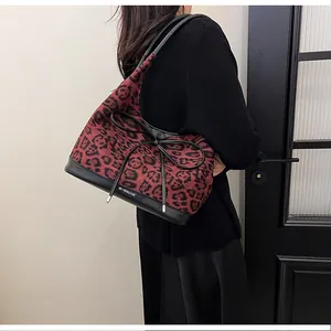 Side view of leopard print tote bag with black leather straps and bow detail