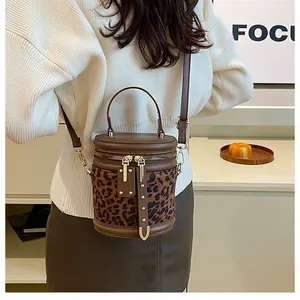 Detail of leopard print cylinder bucket bag with gold studs shown on a female model
