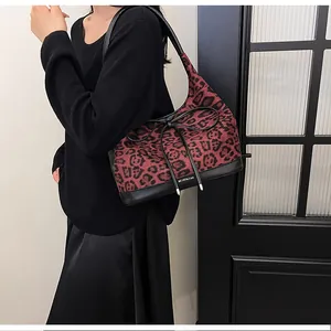 Detail of red leopard print tote bag with black leather straps and bow decoration