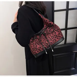 Detail view of large leopard print hobo tote bag with black bow on a model's shoulder
