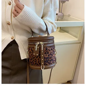 Detail of leopard print bucket bag featuring brown leather trim and golden hardware