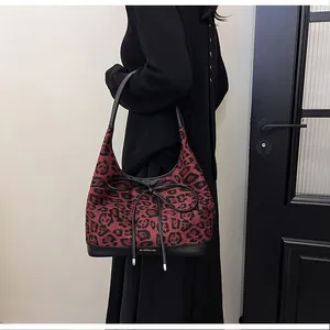 Detail of red leopard print tote bag with black leather bow and brand logo accent