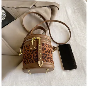 Detail of leopard print cylinder bucket bag with gold hardware and leather straps