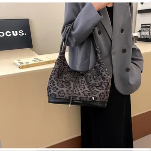 Detail of leopard print tote bag with black bow and leather bottom on model