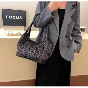 Detail of leopard print tote bag with black leather trim and small bow accent on a model