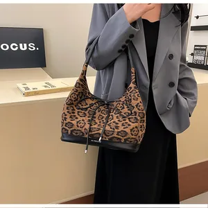 Detail of leopard print tote bag featuring a black leather base and delicate bow accent