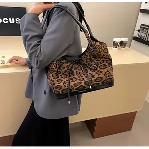 Detail of leopard print tote bag with black bow and reinforced base on a model