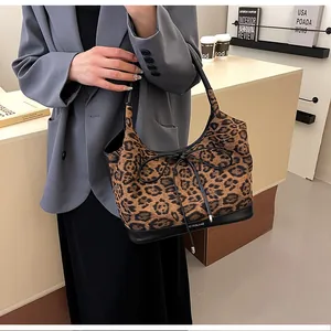 Detail view of leopard print tote bag featuring a black leather bow and reinforced bottom