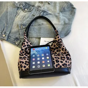 Flat lay of leopard print tote bag with black leather handles next to a tablet and jacket