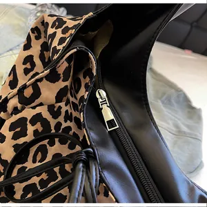 Close-up of leopard print fabric with black leather trim and silver zipper on tote bag