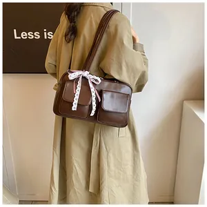Detailed view of brown PU leather tote featuring dual flap pockets and white lace bow