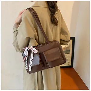 Detail view of large dark brown tote bag with retro pockets and white lace bow accessory