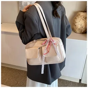 Close-up of beige tote bag with twin front pockets and decorative lace bow on strap