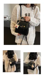 Detail of black leather backpack with dachshund patch and plush bear charm accessory