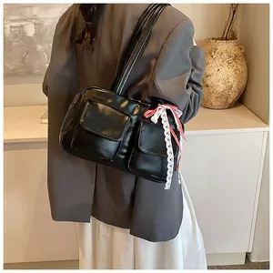 Detail of black glossy shoulder bag with plaid ribbon and lace bow on modern strap