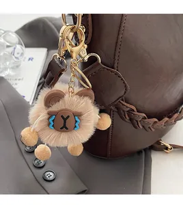 Nahaufnahme eines Plüschbär-Anhängers mit goldenem Clip an einer gewebten Tasche