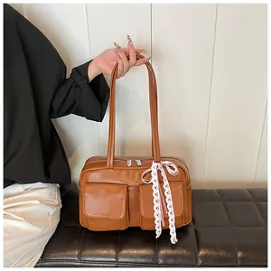 Detail of vintage brown tote bag with twin front pockets and decorative white lace bow