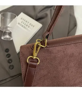 Dettaglio della borsa in pelle scamosciata marrone con fibbia in metallo dorato
