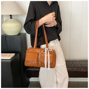 Close-up of vintage brown tote bag featuring decorative lace bows and dual front pockets