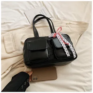 Detail view of black glossy leather tote with cargo pockets and decorative bows